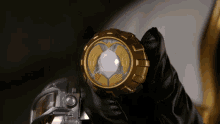 a person in a black glove is holding a gold item