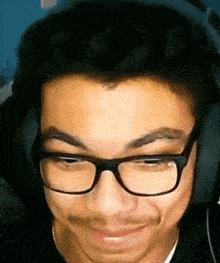 a young man wearing glasses and headphones looks at the camera