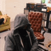 a man wearing a hoodie with the word nb on it sits in a chair