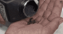 a person is holding a bottle of black ink in their hand .