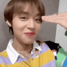 a close up of a person making a funny face while wearing a striped shirt and a necklace .