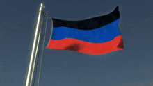 a blue red and black flag is flying on a pole