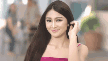 a woman in a pink top is smiling and holding her hair