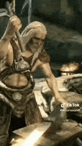 a man with a beard is holding a sword and an axe in a video game .