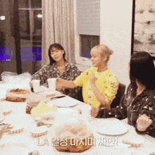 a group of women are sitting at a table with la written on the bottom of the screen