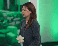 a woman in a grey sweater is standing in front of a green background