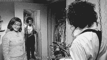 a black and white photo of a woman looking at herself in a mirror and a man saying you look fine just fine