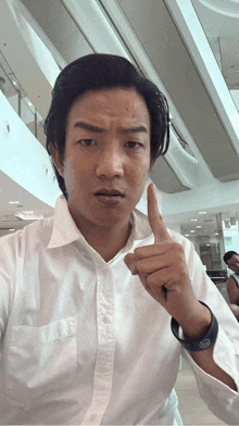 a man in a white shirt is making a funny face and pointing up