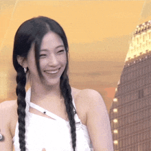 a woman with braids is smiling and wearing a white top
