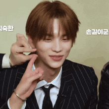 a man in a suit and tie is being touched by someone 's hand
