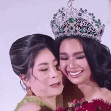 a woman wearing a crown is hugging her mother