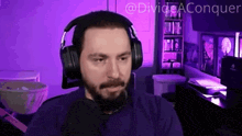 a man with a beard wearing headphones and a microphone with the words divide aconquer above him