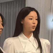 a woman wearing a white shirt with puffed sleeves is looking at the camera