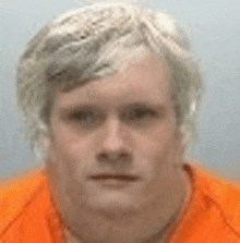 a man wearing an orange shirt is looking at the camera .