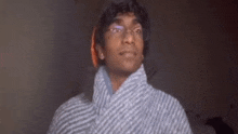 a young man wearing glasses and a striped robe is looking at the camera .