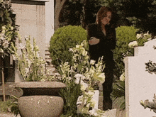 a woman in a black suit stands in front of a grave
