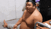 a man without a shirt is sitting on the floor