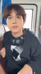 a young man wearing headphones and a black hoodie looks up at the camera