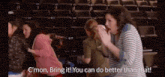a group of women are sitting in an auditorium and one of them is saying " c 'mon bring it you can do better than that "