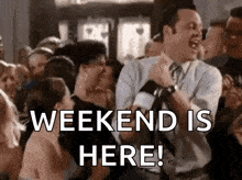 a man in a suit and tie is dancing in a crowd with the words `` weekend is here '' .