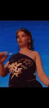 a woman in a black dress is standing in the desert with her hands on her chest .
