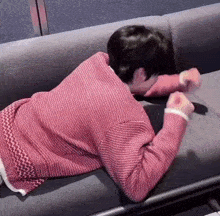 a person wearing a red sweater is laying on a couch