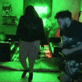 a man and a woman are dancing in a living room with a neon sign that says ' studio ' on it
