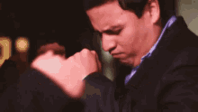 a man in a suit and bow tie is adjusting his bow tie