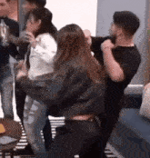 a group of people are dancing together in a room while a man holds a woman .