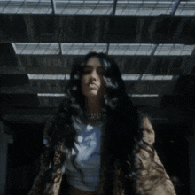 a woman with long black hair is wearing a white tank top and leopard print jacket