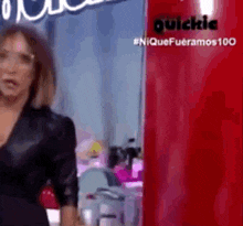 a woman in a black dress is standing in front of a red refrigerator that says quickie