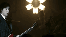 a man in a suit and tie is playing a red guitar