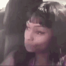a woman is sitting in the back seat of a car with her eyes closed and her hair in a bun .