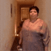 a woman is standing in a hallway with a cell phone in her hand .