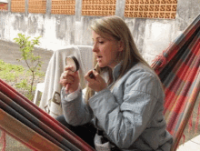 a woman in a hammock is applying lipstick