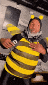a man with a beard is dressed as a bee and holding his chest .