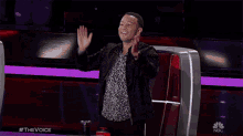 a man applauds while sitting in front of a screen that says nbc on it