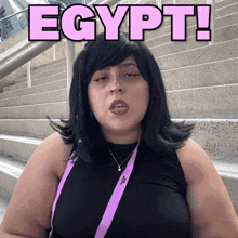 a woman wearing a black tank top and a purple lanyard with the word egypt on it