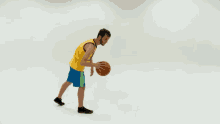 a basketball player in a yellow jersey and blue shorts is dribbling the ball