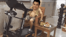 a man is sitting on a chair next to a treadmill that says sport on it