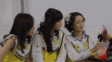 three girls wearing uniforms with the letter k on them are looking at something