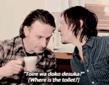 two men are talking to each other and one of them is holding a cup of coffee