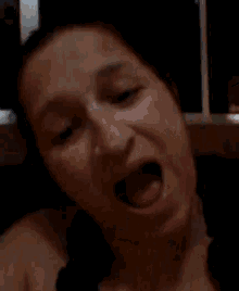 a close up of a woman 's face with her mouth wide open