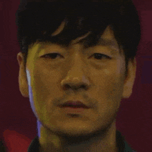 a close up of a man 's face with a beard looking at the camera with a red background .