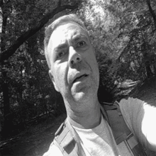 a man taking a selfie in the woods with a backpack