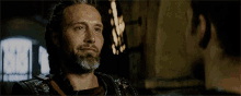 a man with a beard is smiling while looking at another man