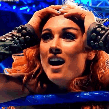 a woman with a surprised look on her face is holding her head in a wrestling ring .