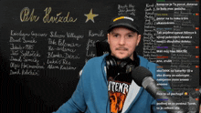 a man wearing headphones stands in front of a blackboard with the word petr written in white
