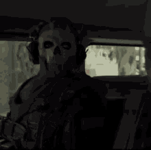 a man wearing a skull mask and headphones is sitting in the back seat of a car