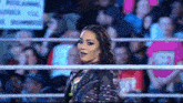 a woman in a wrestling ring stands in front of a crowd with a sign that says ' rules ' on it